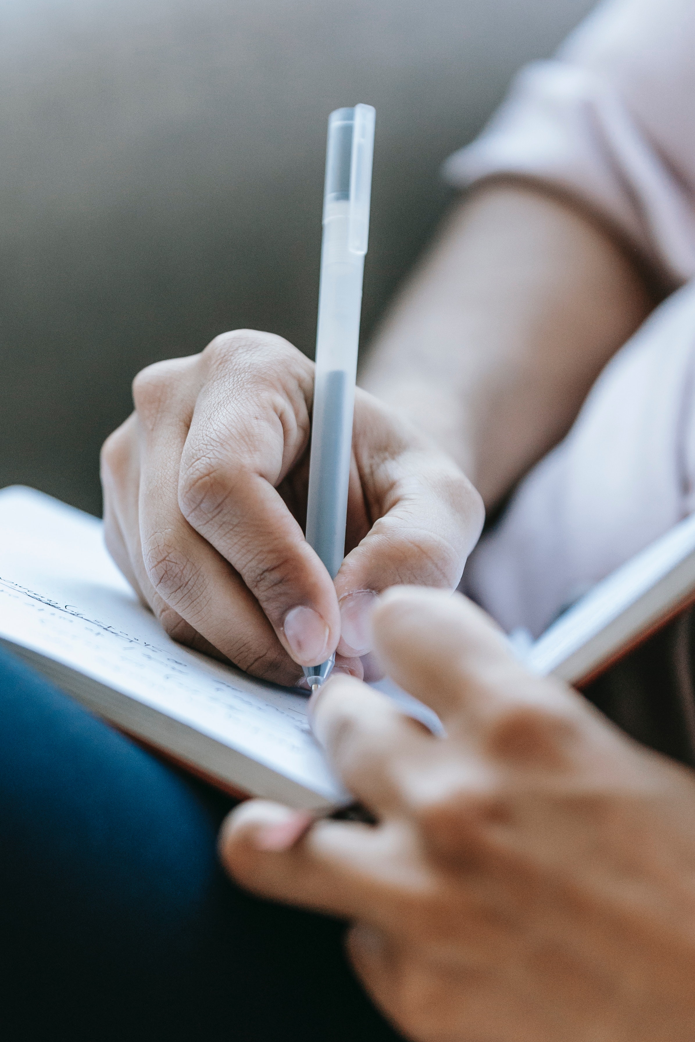 Close-up of writer's hands holding a pen and notebook